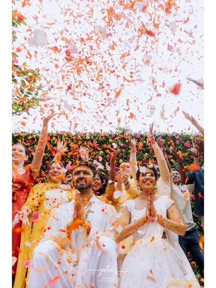 There is nothing more joyful than a shower of petals. For this Haldi, we created a moment of pure magic as the couple was blessed by friends and family under a rain of colorful flowers, set against a vibrant floral wall.