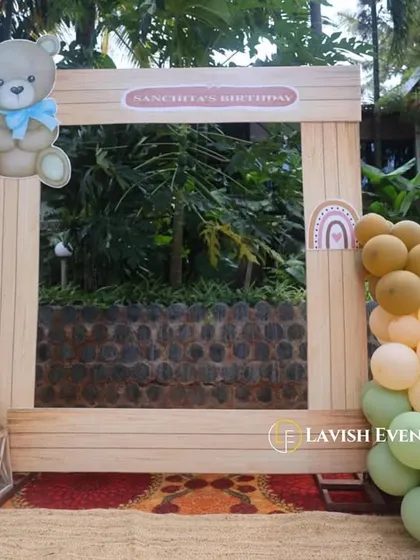 A custom wooden photo booth frame designed for a teddy bear themed party, complete with a cute bear cutout and a matching balloon garland.