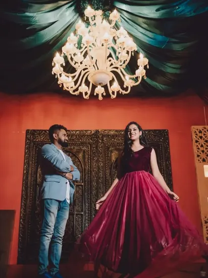 A stylish pre-wedding shot under a chandelier. The flowing skirt of the maroon gown is perfect for creating movement.
