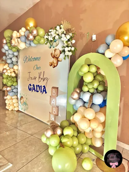 A detailed shot of the 'Welcome Baby Gadia' setup, highlighting the balloon-filled arch prop and the combination of fresh flowers and balloons on the main backdrop.