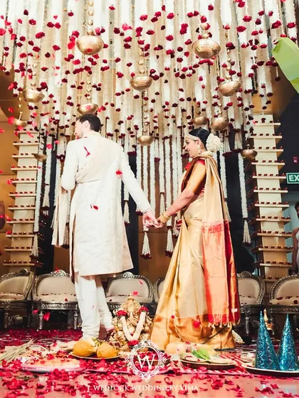 A beautiful moment from a traditional South Indian wedding. The mandap is decorated with red and white floral garlands, with rose petals showering the happy couple as they complete their rituals.