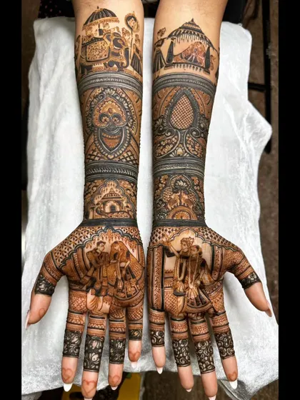 This intricate bridal mehendi features a beautiful portrait of the couple exchanging garlands, a classic varmala scene. The forearms are adorned with traditional baraat procession elements, including elephants and palanquins.