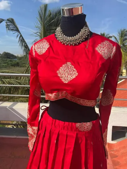 A close-up of the red blouse with gold motifs.