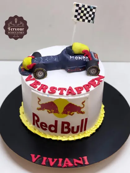 A Red Bull racing car theme cake for a Ferrari fan. The cake features the Red Bull logo and a hand-molded F1 car on top.