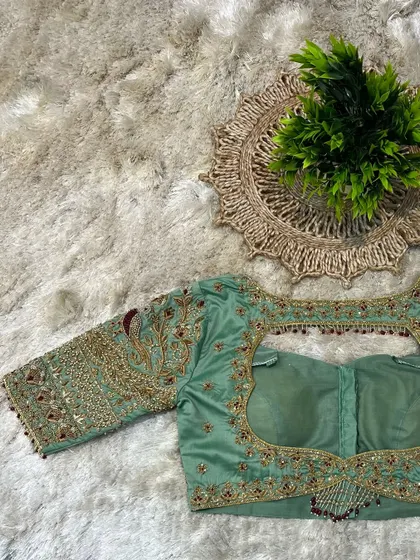 The back of the pastel green blouse, with a large cut-out framed by heavy beadwork and embroidery.