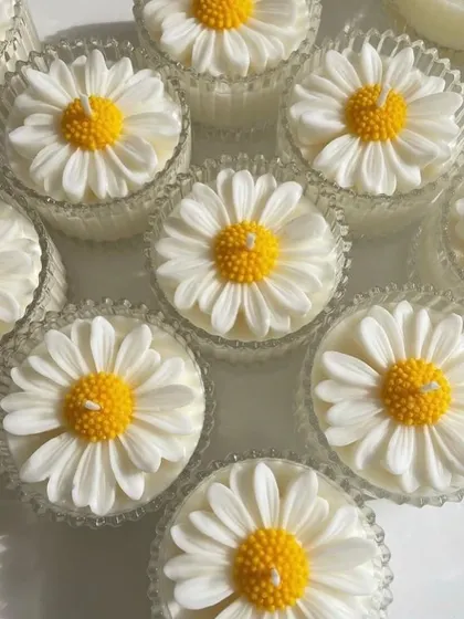 A close-up of the daisy candles in mini crystal candy jars. The textured glass catches the light beautifully.