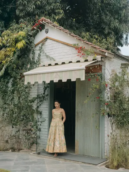A bride posing by our charming cottage-style building, a beautiful backdrop for portraits.