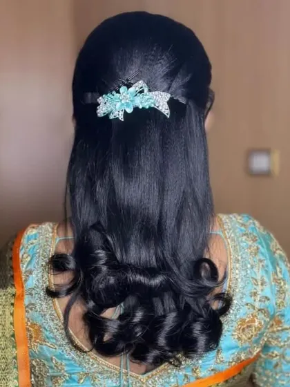 A sleek half-up style with curled ends, adorned with a modern, sparkling light blue floral clip.