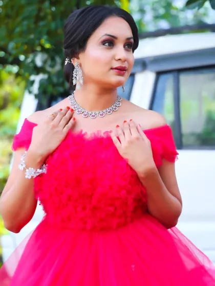 A full view of the modern party look. The bright red gown, sparkling jewellery, and polished makeup and hair create a head-turning ensemble for any special event.