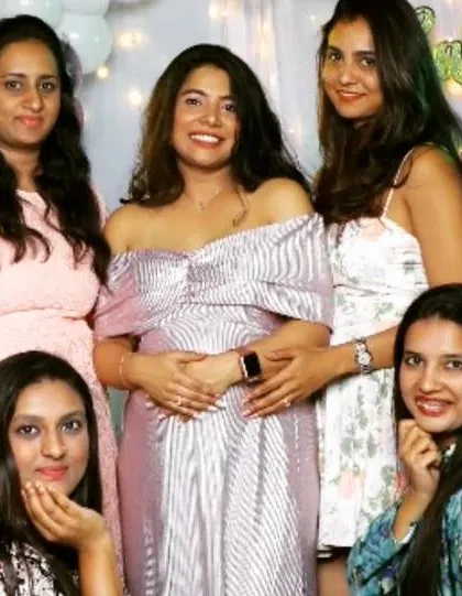 A happy mom-to-be surrounded by friends at her baby shower in my shimmering pink off-the-shoulder gown. It's a perfect party dress for your special celebration.