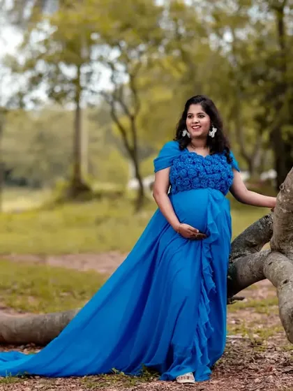 The full length of the sky blue tail gown is showcased in this outdoor shot. The dress is designed to be both comfortable and visually stunning for maternity portraits.