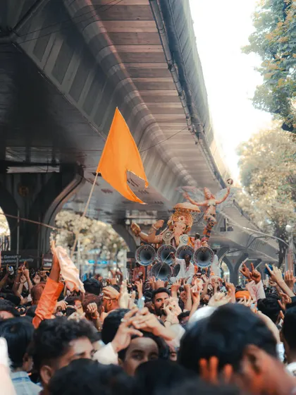 The procession moving under a flyover, with an orange flag flying high. This image captures the unstoppable energy and devotion of the crowd.