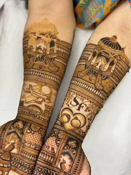 A close-up of a personalized engagement mehandi, showing the doli, airplane, and initials. The details are sharp and clear.