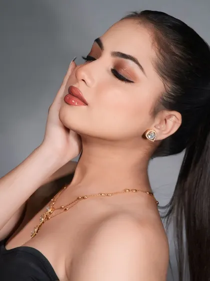 A soft, elegant beauty shot focusing on a simple gold chain and heart-shaped stud earrings. This demonstrates my versatility in shooting both heavy and delicate jewelry pieces.