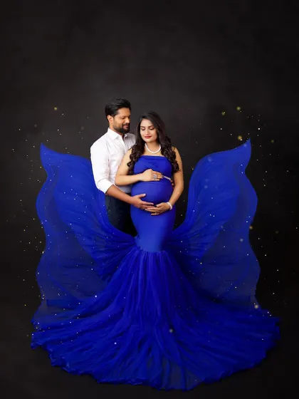 A magical couple's portrait in royal blue. The fabric wings and sparkling lights create a celestial, fairytale atmosphere, celebrating their journey together.
