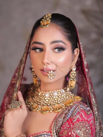 A side profile of this stunning bride, highlighting the flawless base, intricate jewelry, and the overall elegance of her traditional look.