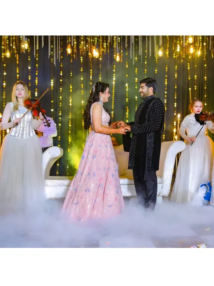 A romantic moment on stage, with the couple surrounded by dry ice and violinists. This shot captures the dreamy, fairytale atmosphere of their engagement.