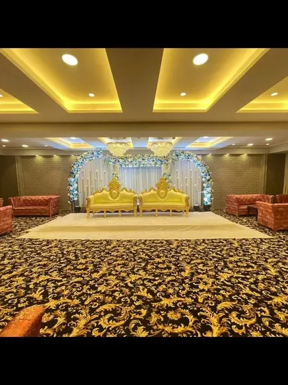 The stage and seating at Palm Beach banquet, available with a special discount. The patterned carpet and golden sofas add to the hall's charm.