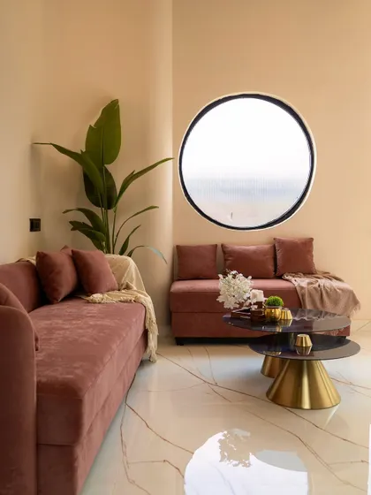A closer look at the lounge seating, highlighting the soft textures and the simple, elegant styling with a large plant adding a natural element.