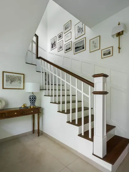 A classic staircase from a Victorian remodel. The white spindles contrast beautifully with the dark wood handrail and treads, and a gallery wall of black and white photos adds a personal touch.