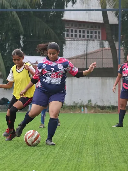 A player from our girls' team looks to make a pass during a league match. This photo captures the focus and game awareness we train our players to have.