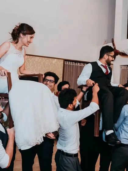 The full scene of the Hora dance, with friends and family lifting the bride and groom on chairs in a joyous celebration.