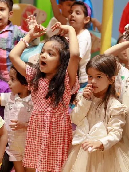 A group of girls singing and dancing along with the entertainment at a birthday party.
