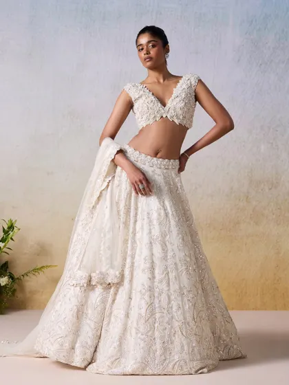 An ivory and gold lehenga that exudes timeless elegance. The hand-embroidered details and classic silhouette make this a perfect choice for a bride seeking understated luxury for her wedding day or reception.