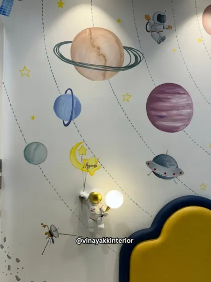 A close-up of our custom space-themed wall mural. The hand-painted planets and astronaut wall lamp, personalized with the child's name, make the room feel truly special and unique.