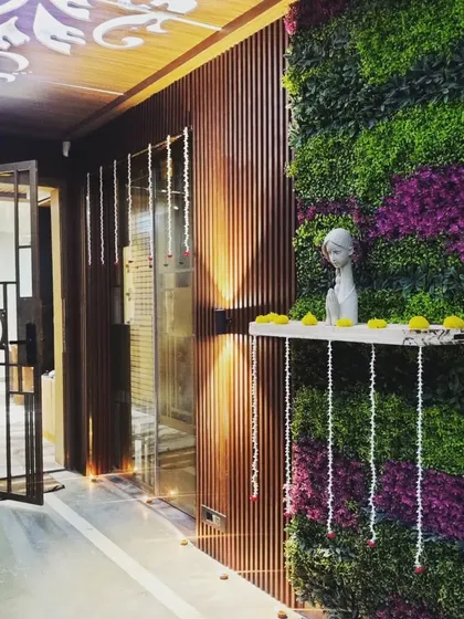 We designed this elegant entryway to welcome residents home with a touch of nature. The combination of a lush vertical garden with purple accents, warm wood louvers, and soft up-lighting creates a sophisticated and serene first impression.