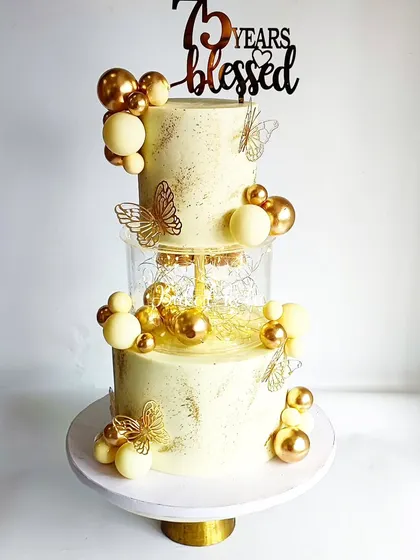A closer look at the 75th birthday cake, showing the delicate gold butterflies and chocolate spheres.
