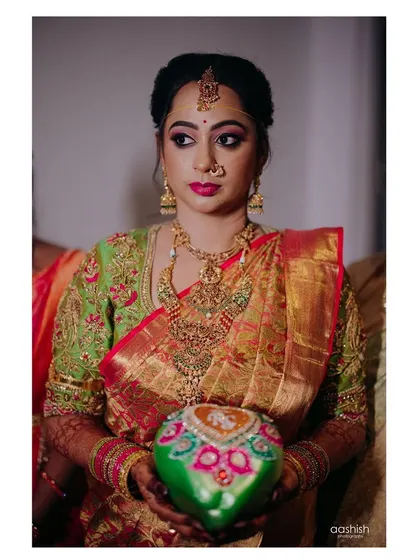 Our bride holding a decorated coconut, a traditional part of the ceremony. Her parrot green blouse with intricate bird motifs is a standout piece.