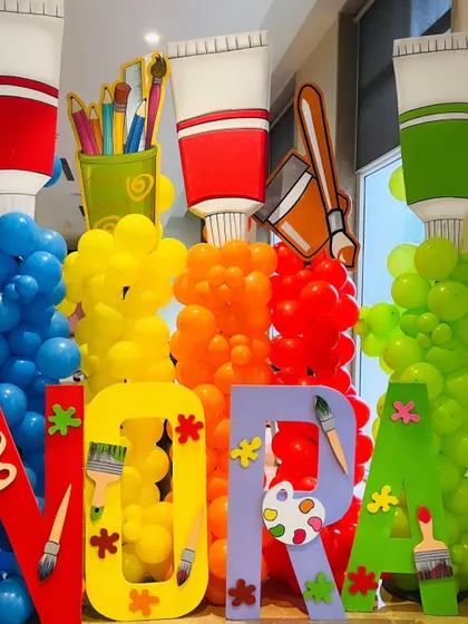 Large, colorful letters spelling out "NORA," each decorated with art supplies, creating a fantastic, personalized photo opportunity.