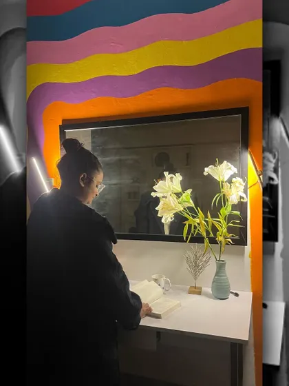 A model interacting with the rainbow set. The design includes a small vanity and mirror, making it a functional and aesthetic corner within the studio.