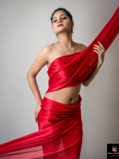 A fine art concept titled 'CRIMSON DREAMS'. The model is draped in a flowing red fabric, creating a sculptural and abstract form that is both powerful and elegant.