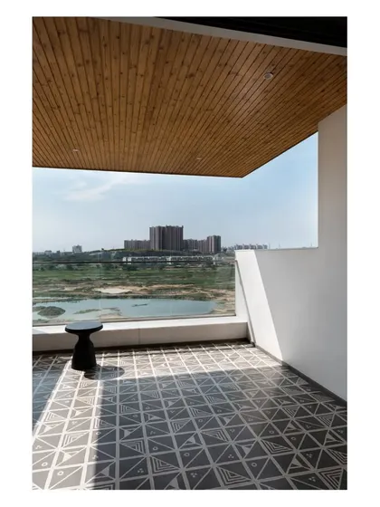 The living room in the 'House of Skye' opens onto a large balcony with views of Hulimavu Lake. The flooring of patterned cement tiles continues the interior's crafted feel into the outdoor space.