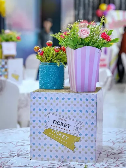 Another view of the carnival table centerpiece, showcasing the blend of fresh flowers and sweet treats. The themed elements like the ticket-adorned box tie the entire table setting together.