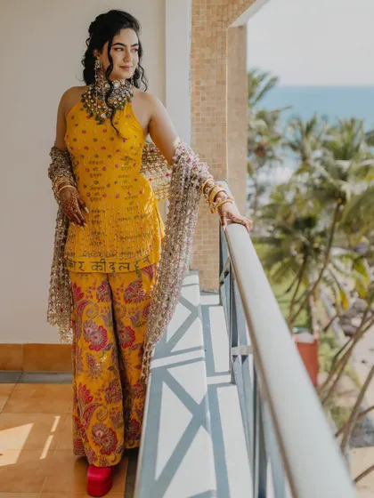 The bride enjoying a moment on the balcony, with the sea and palm trees in the background. This shot perfectly captures the destination wedding vibe of their Goa Haldi.