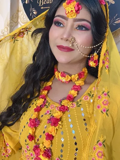A classic Haldi look with a yellow outfit and floral jewellery. The makeup features pink and yellow tones on the eyes to match the flowers, creating a cohesive and vibrant look.