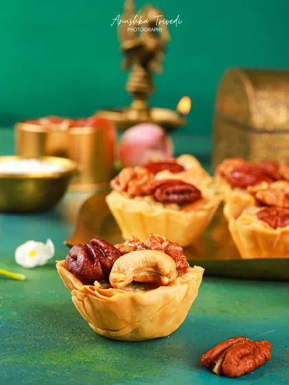 A macro shot of a single mini nut tart, focusing on the texture of the flaky crust and the glossy nuts.