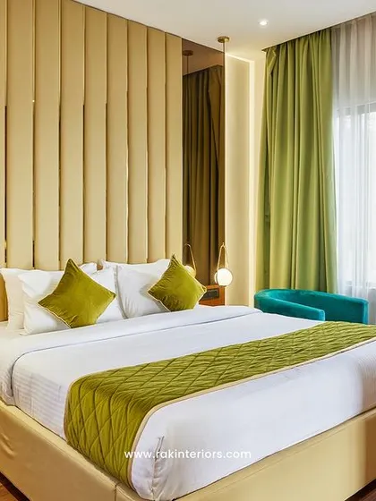 This room features a floor-to-ceiling upholstered headboard that acts as a dramatic focal point. Mirrored side panels and modern drop lighting add a sense of space and sophistication to the hotel room interior.