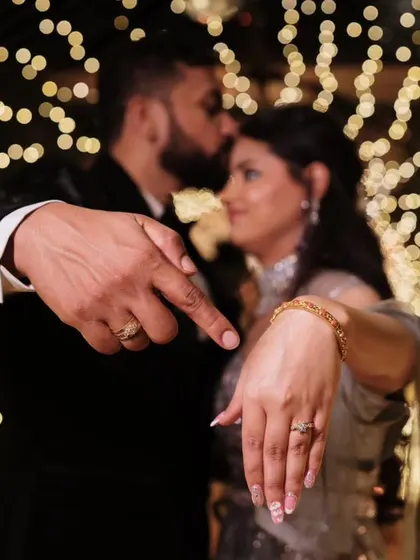 A creative and symbolic shot focusing on the engagement rings, with the couple sharing a tender moment in the beautifully blurred, bokeh-filled background.