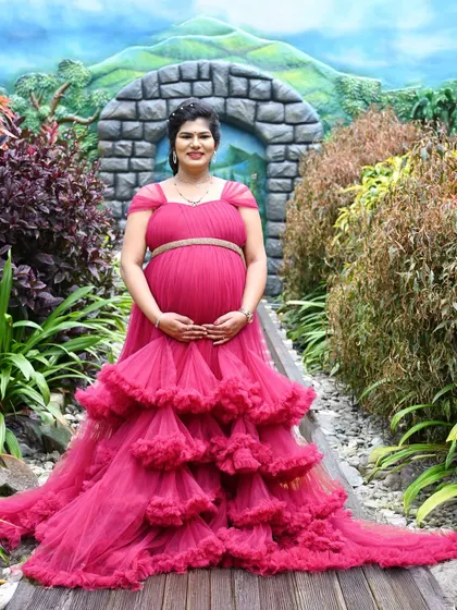 A gorgeous outdoor portrait in a lush garden setting. The tiered pink gown looks absolutely stunning against the natural greenery.