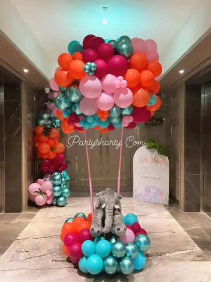 A stunning hot air balloon sculpture made of vibrant balloons, with a plush elephant in the basket, perfect for a jungle or travel-themed party.