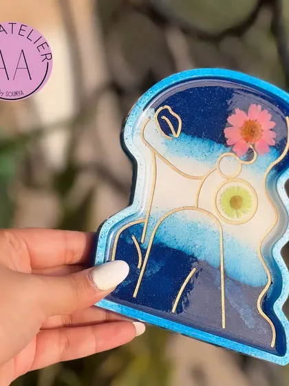 This lady-figure trinket tray in shades of blue is a stylish way to organize your jewelry or small essentials. The embedded flower adds a delicate, artistic touch.