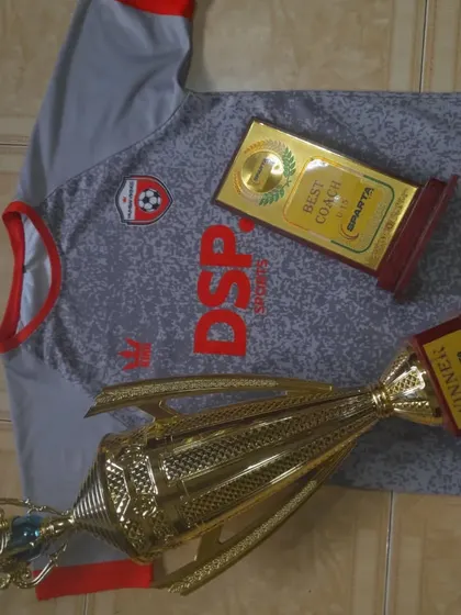 Another angle on our achievements. This shot features a large winner's trophy and a "Best Coach" plaque, representing the combination of player talent and expert guidance that leads to victory.