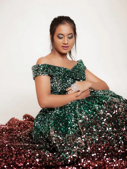A seated shot from the same series, with the ombre sequin dress pooled around the model. This creates a dramatic and glamorous effect.
