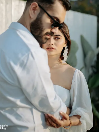 A modern and artistic pre-wedding portrait. The bride's gaze meets the camera from behind the groom's embrace, creating a sense of intimacy and connection.