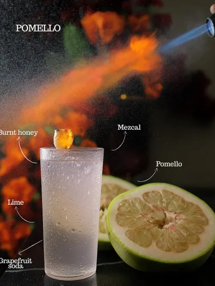 The Pomello cocktail, a fiery mix of burnt honey, mezcal, lime, and grapefruit soda. The blowtorch caramelizes the honey, adding a smoky depth to this refreshing drink.
