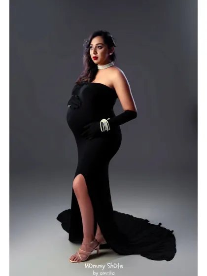 A full-length view of the dramatic black gown for this maternity shoot. The makeup adds to the high-fashion, editorial feel of the photo.